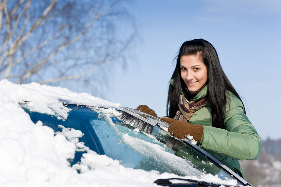 Девушка чистит машину от снега