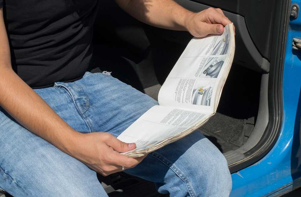 Мужчина читает инструкцию к автомобилю