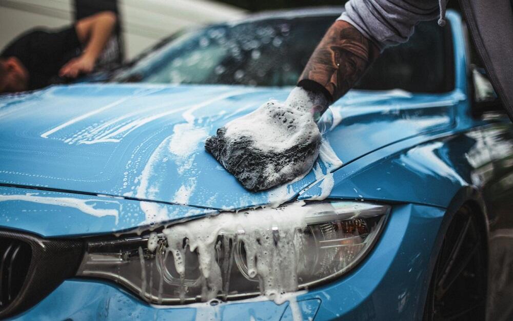 Человек моет голубую машину