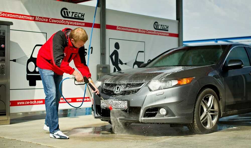 Мужчина моет автомобиль на бесконтактной мойке