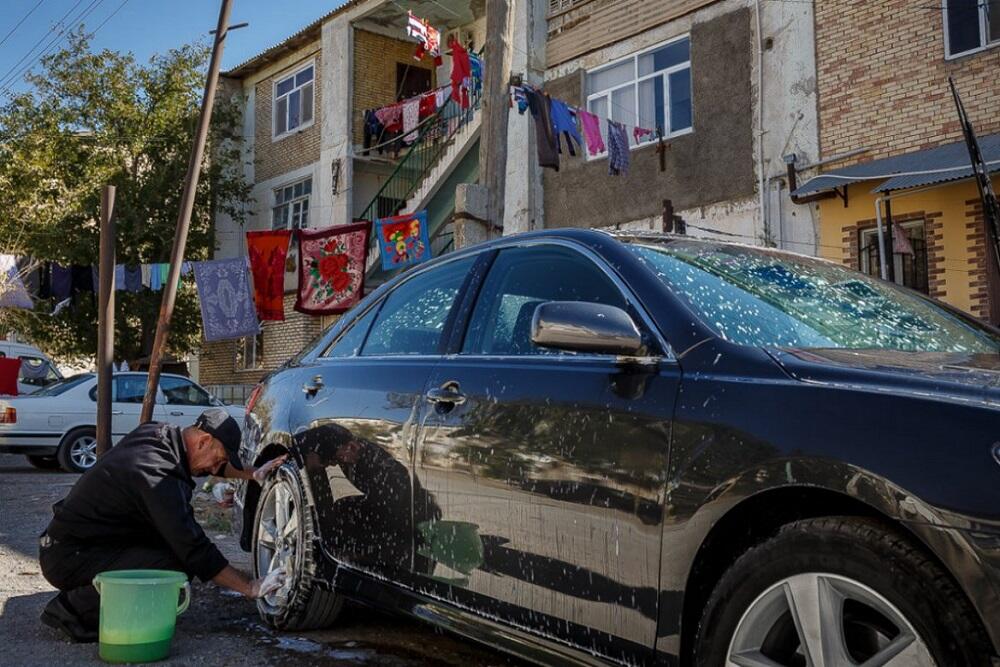 Мужчина моет машину во дворе